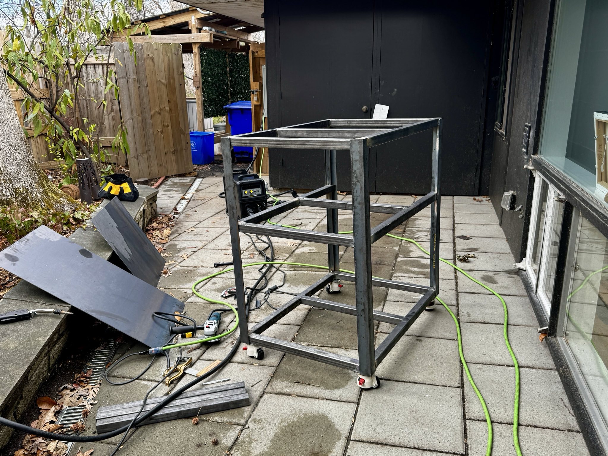 a finished cart made of mild steel, with a welder and welder helmet on a shelf