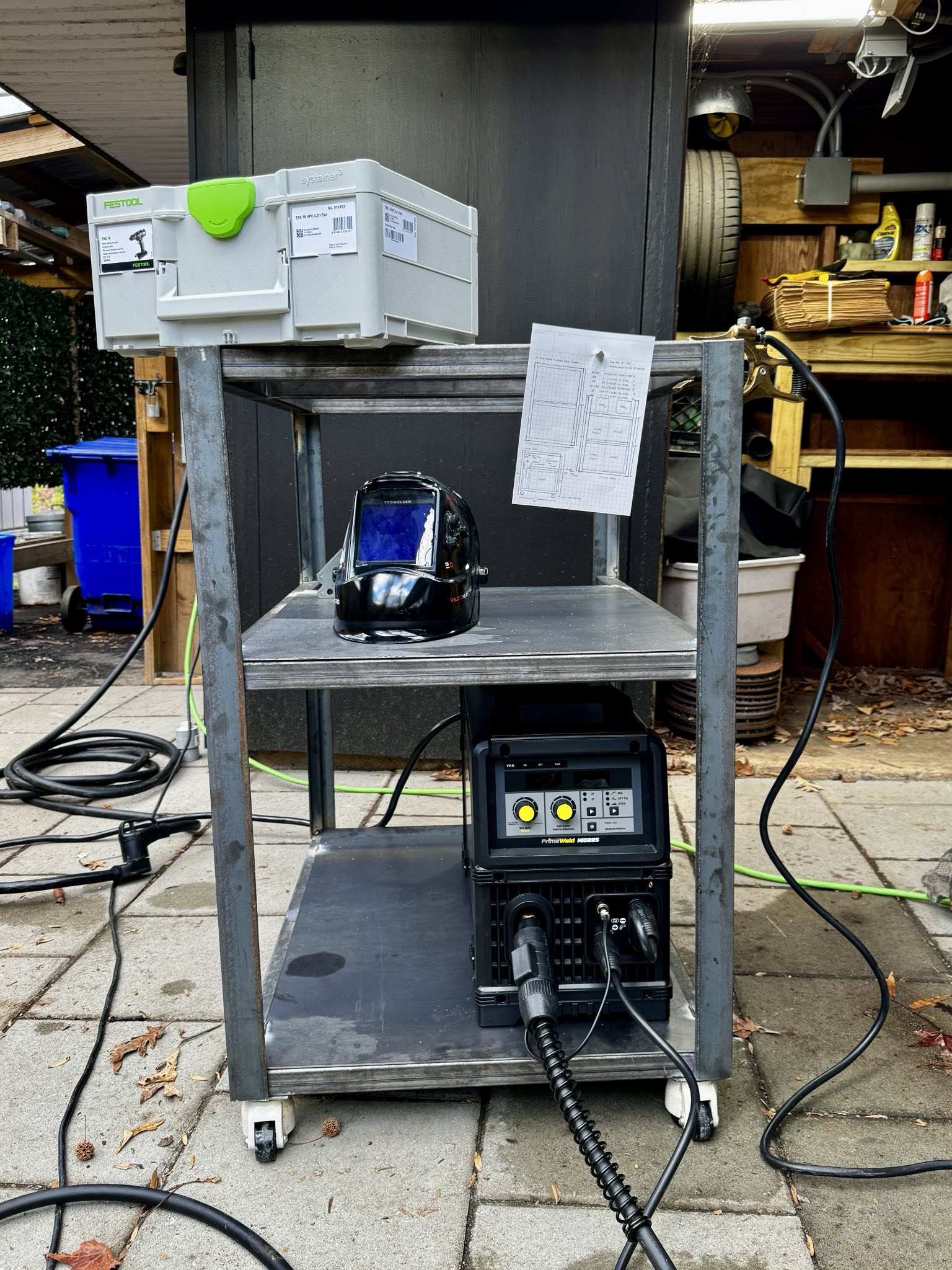 a finished cart made of mild steel, with a welder and welder helmet on a shelf