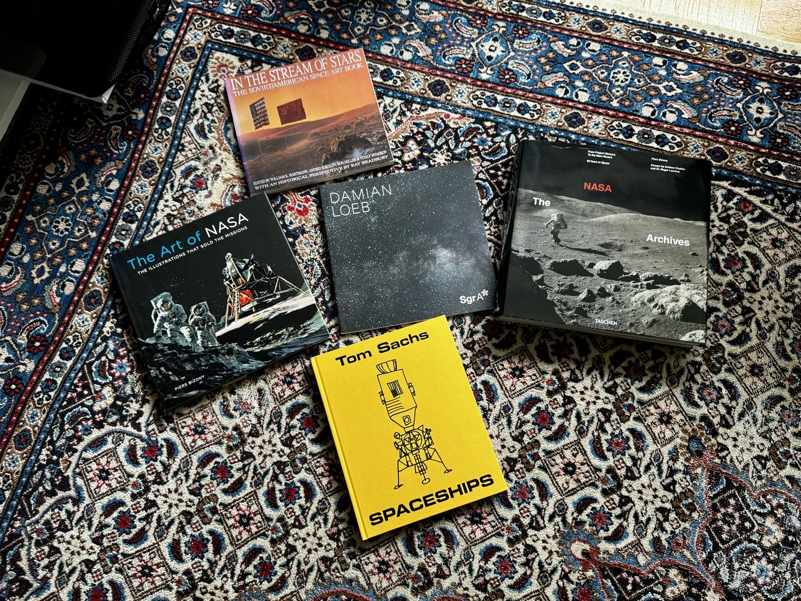 some books about space art on a persian carpet floor